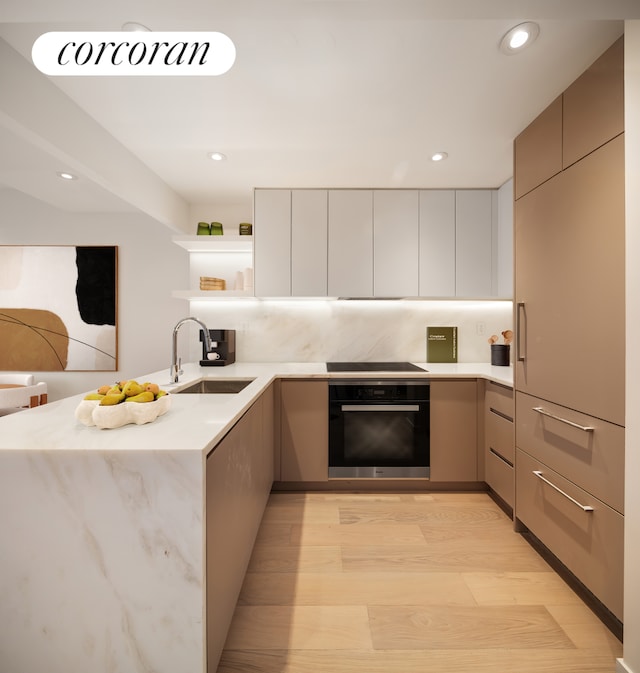 kitchen featuring oven, a sink, open shelves, modern cabinets, and light wood-type flooring