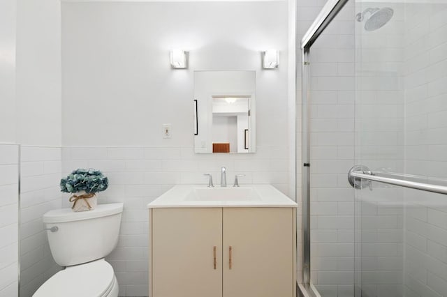 bathroom with tile walls, a shower stall, vanity, a wainscoted wall, and toilet