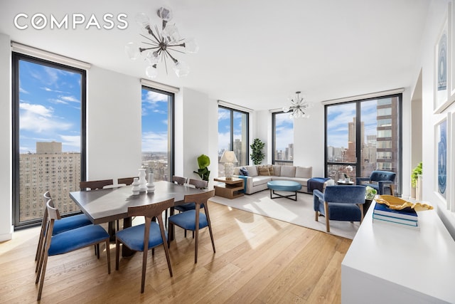 360 E 89th St Unit 29B, New York City, NY 10128 - dining space featuring a chandelier, light wood-type flooring, floor to ceiling windows, a skyline view, and healthy amount of natural light