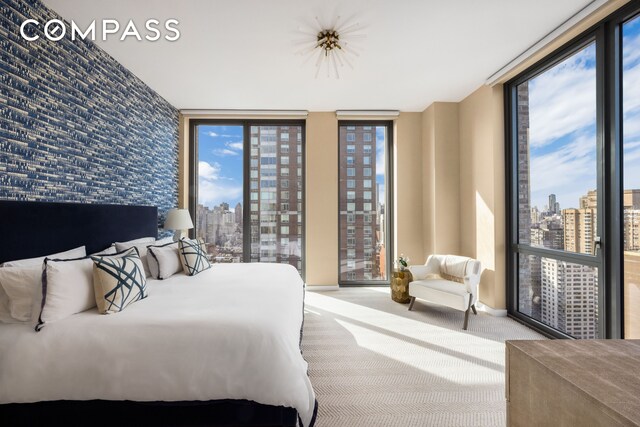 360 E 89th St Unit 29B, New York City, NY 10128 - bedroom featuring a view of skyline, carpet flooring, and a wall of windows