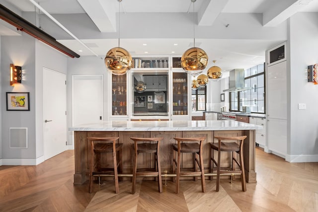 360 W 36th St Unit Ph12, New York City, NY 10018 - kitchen with island exhaust hood, a large island, a breakfast bar, light stone countertops, and baseboards