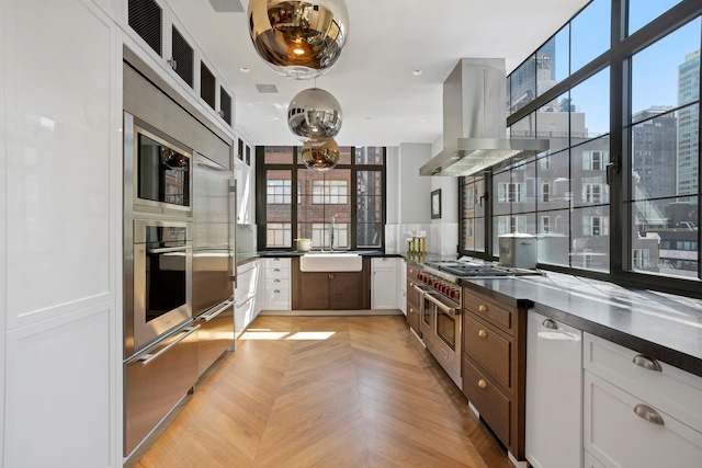360 W 36th St Unit Ph12, New York City, NY 10018 - kitchen with appliances with stainless steel finishes, dark countertops, island exhaust hood, and healthy amount of natural light
