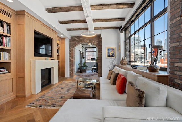 360 W 36th St Unit Ph12, New York City, NY 10018 - living room with beamed ceiling, built in shelves, a fireplace, arched walkways, and parquet floors