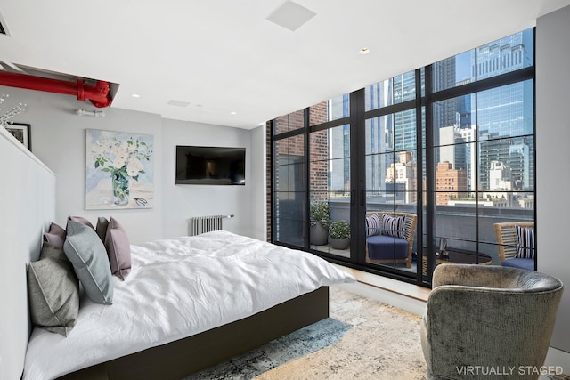 360 W 36th St Unit Ph12, New York City, NY 10018 - bedroom featuring radiator heating unit, expansive windows, and recessed lighting