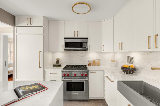 230 E 79th St Unit 12Cd, New York City, NY 10021 - kitchen with premium appliances, tasteful backsplash, white cabinetry, a sink, and light stone counters