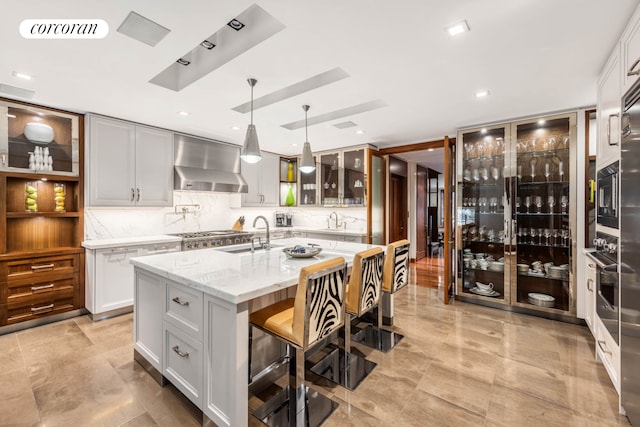 159 E 61st St, New York City, NY 10065 - kitchen with wall chimney range hood, a sink, a kitchen island with sink, and a breakfast bar area