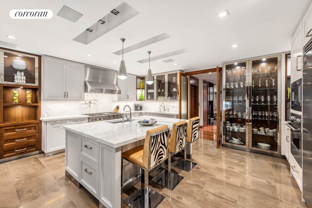 159 E 61st St, New York City, NY 10065 - kitchen with wall chimney range hood, a sink, a kitchen island with sink, and a breakfast bar area