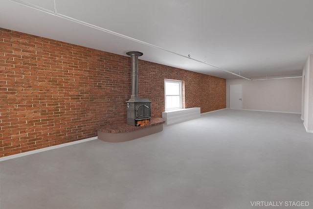 407 E 91st St Unit 5F, New York City, NY 10128 - unfurnished living room featuring brick wall, a wood stove, and baseboards