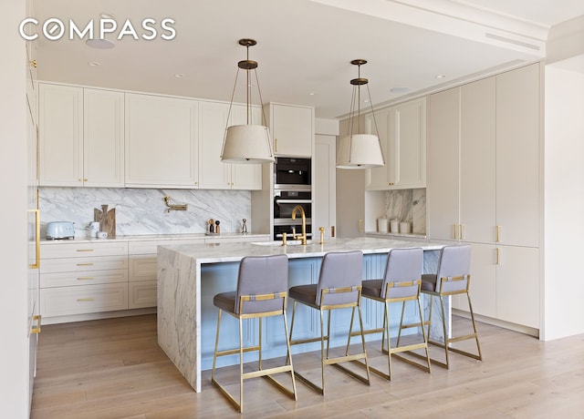 100 W 80th St Unit 5B, New York City, NY 10024 - kitchen featuring backsplash, light wood finished floors, a center island with sink, a breakfast bar area, and white cabinetry