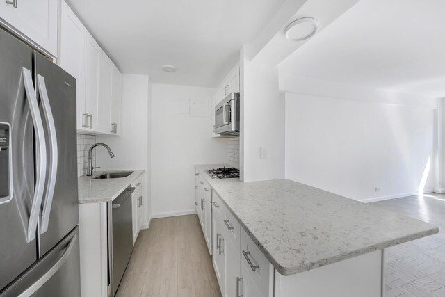 kitchen featuring white cabinetry, appliances with stainless steel finishes, decorative backsplash, and a sink