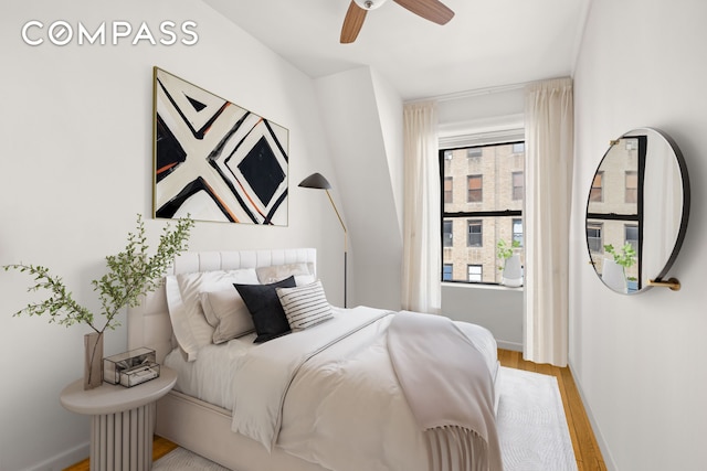 bedroom featuring wood finished floors, baseboards, and ceiling fan