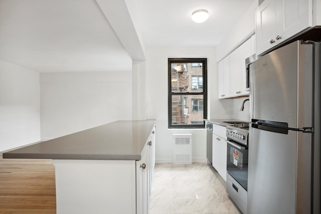 4489 Broadway Unit 5E, New York City, NY 10040 - kitchen with appliances with stainless steel finishes, a peninsula, white cabinets, and light marble finish floors