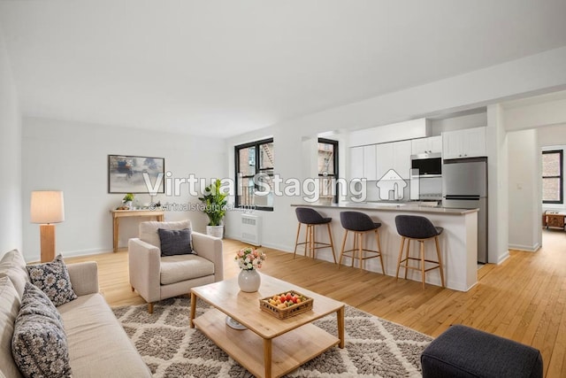 4489 Broadway Unit 5E, New York City, NY 10040 - living area featuring light wood-style floors and radiator