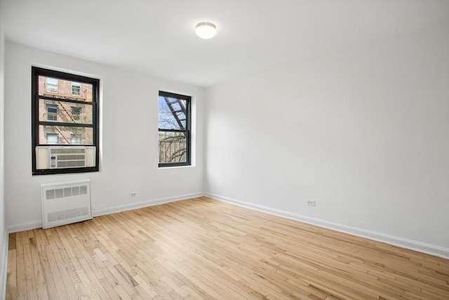 4489 Broadway Unit 5E, New York City, NY 10040 - empty room with radiator heating unit, cooling unit, and light wood-style flooring