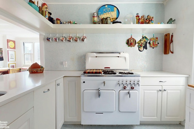 kitchen featuring white gas range oven, white cabinetry, and light countertops
