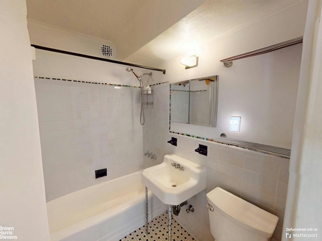 bathroom with a sink, toilet, tile walls, and shower / tub combination