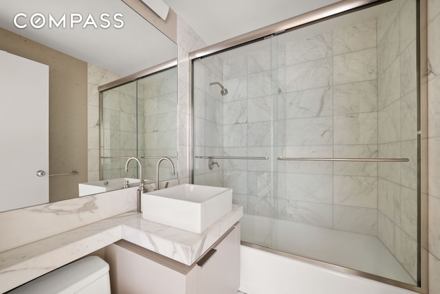 full bath featuring toilet, vanity, and shower / bath combination with glass door