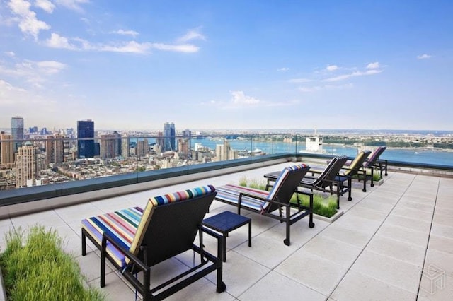view of patio with a balcony, a view of city, and a water view