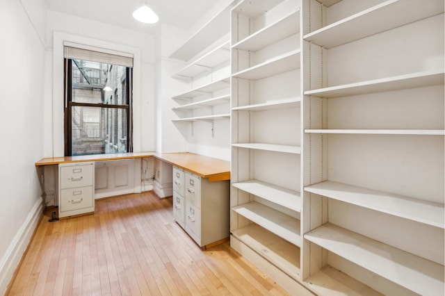 unfurnished office with built in study area and light wood-style floors