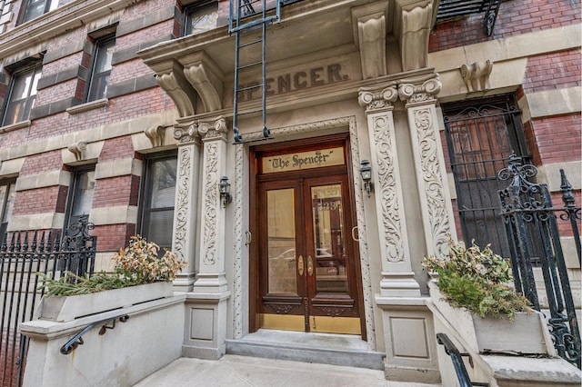 property entrance with brick siding, fence, and french doors
