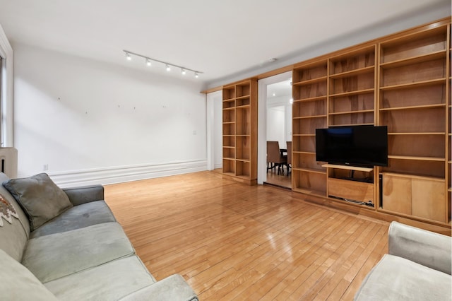 living area featuring track lighting, baseboards, and hardwood / wood-style flooring