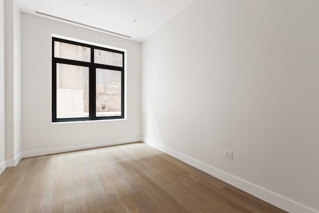 spare room with baseboards and wood finished floors