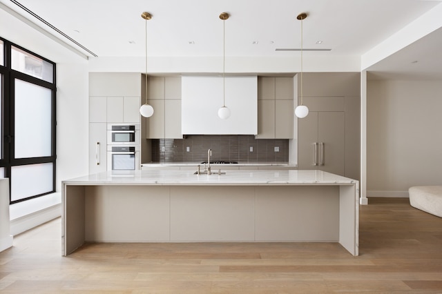 kitchen featuring light wood-style floors, decorative backsplash, modern cabinets, and a spacious island