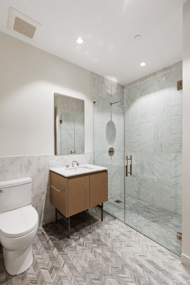 bathroom featuring visible vents, tile walls, a stall shower, vanity, and toilet