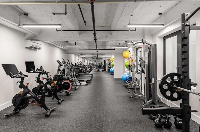 workout area featuring baseboards and a wall unit AC