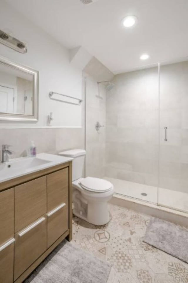 bathroom with tile patterned floors, toilet, a stall shower, and vanity