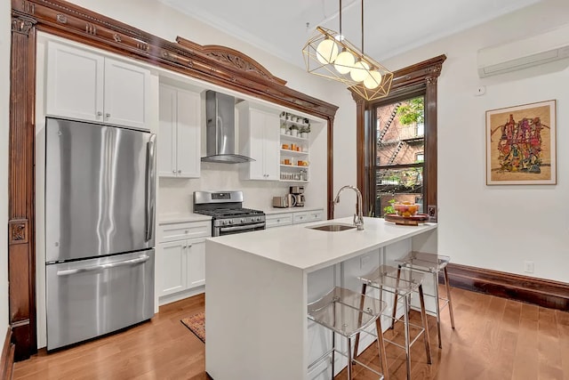 kitchen with light wood-type flooring, wall chimney range hood, a sink, an AC wall unit, and stainless steel appliances