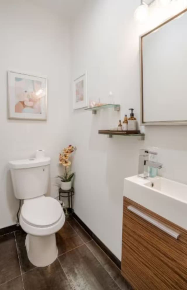 bathroom with tile patterned flooring, vanity, baseboards, and toilet