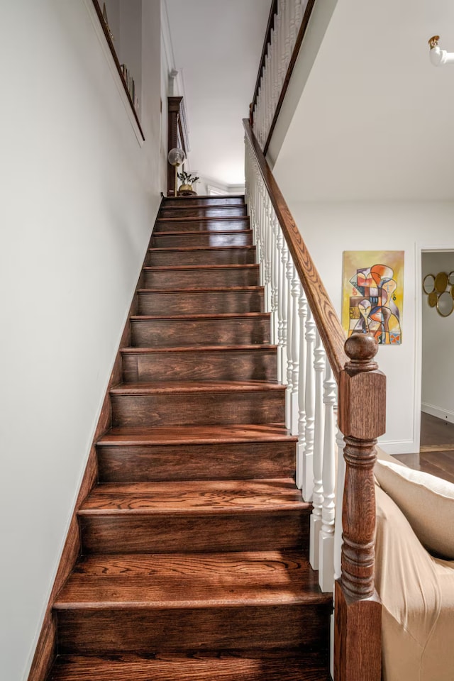 stairway featuring a high ceiling and baseboards