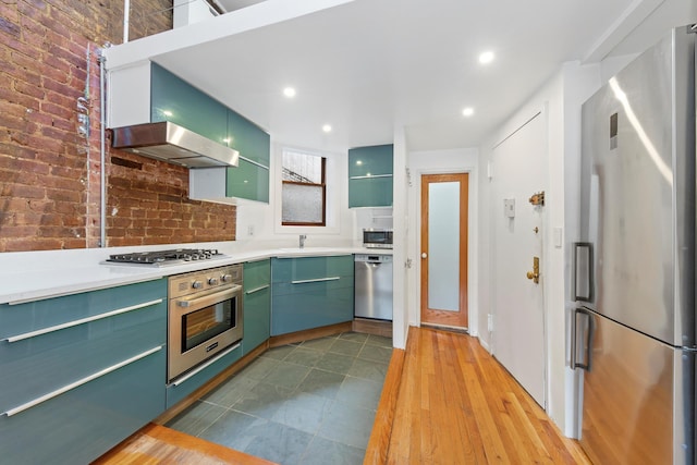 331 E 92nd St Unit 5C, New York City, NY 10128 - kitchen with stainless steel appliances, green cabinets, a sink, range hood, and light countertops