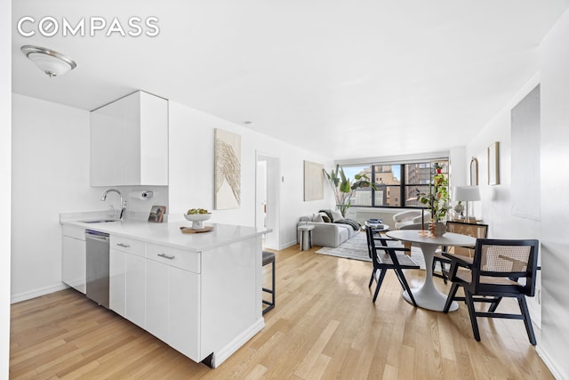 kitchen with stainless steel dishwasher, a sink, white cabinetry, and modern cabinets