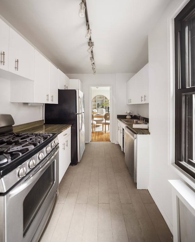 140 7th Ave Unit 4L, New York City, NY 10011 - kitchen featuring appliances with stainless steel finishes, dark countertops, white cabinets, and radiator