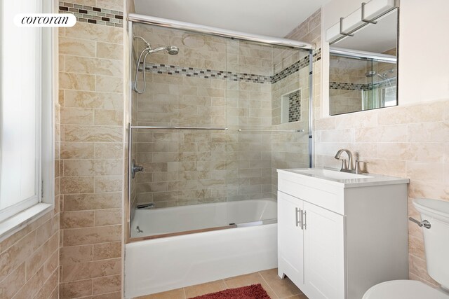 bathroom with shower / bath combination with glass door, tile walls, toilet, and tile patterned floors