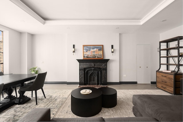 living area featuring a tray ceiling, wood finished floors, a fireplace, and crown molding