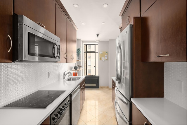 kitchen with appliances with stainless steel finishes, a sink, light countertops, decorative backsplash, and recessed lighting