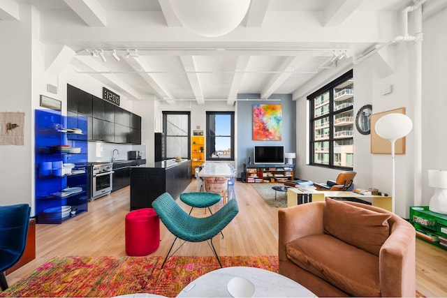 448 W 37th St Unit 9A, New York City, NY 10018 - living room featuring light wood finished floors, beamed ceiling, and healthy amount of natural light