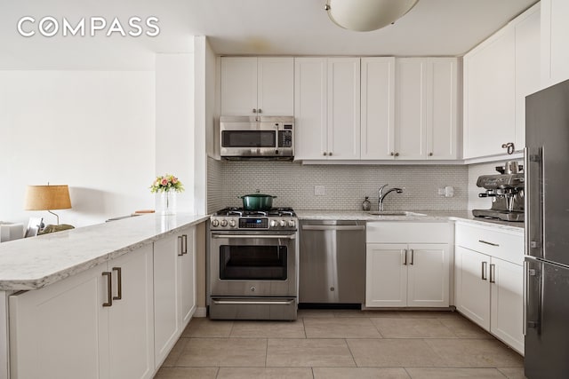 22 W 15th St Unit 10G, New York City, NY 10011 - kitchen with stainless steel appliances, a peninsula, white cabinetry, and backsplash