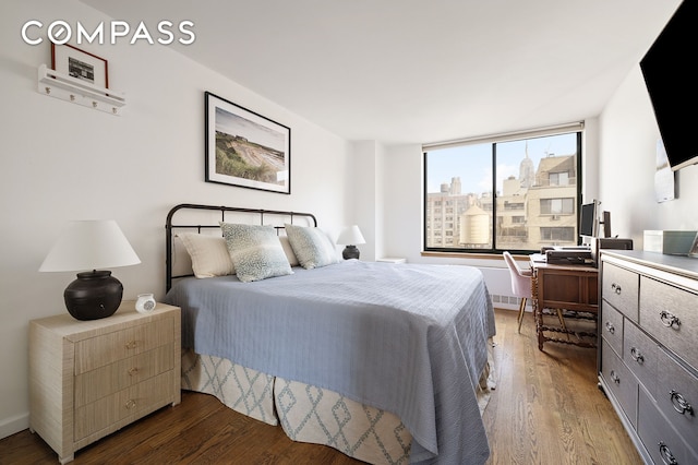 bedroom featuring wood finished floors, an office area, and baseboards