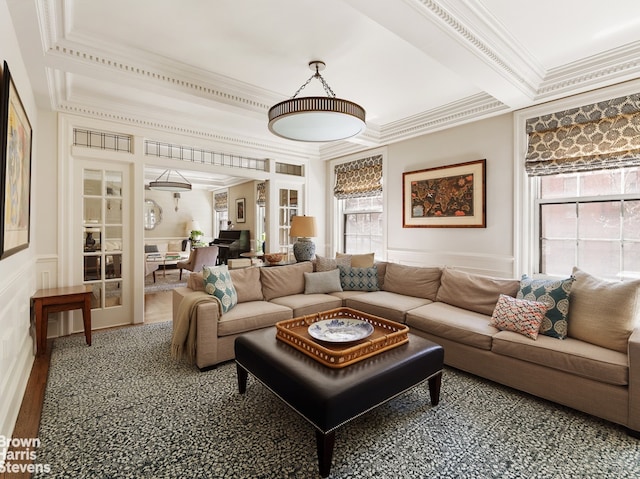 living room featuring crown molding, healthy amount of natural light, a decorative wall, and wainscoting