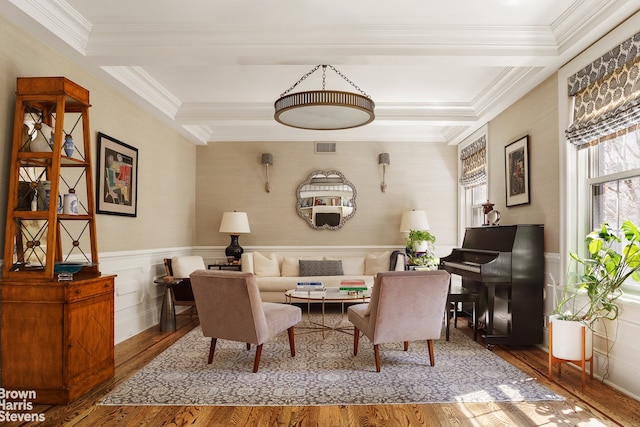 living area with wood finished floors, crown molding, and wainscoting