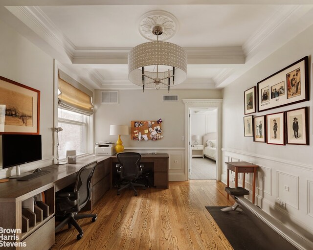 office space featuring wood finished floors, a wainscoted wall, a raised ceiling, and crown molding