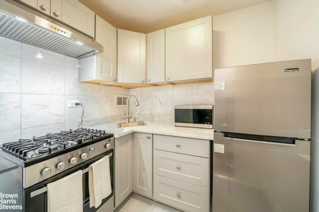 330 E 49th St Unit 3L, New York City, NY 10017 - kitchen featuring appliances with stainless steel finishes, under cabinet range hood, decorative backsplash, light stone countertops, and a sink