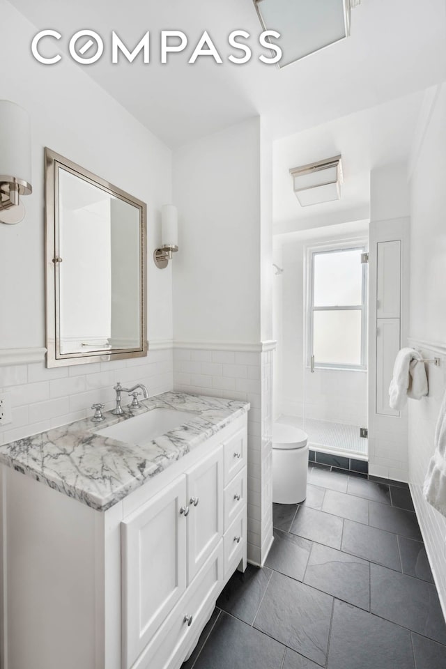 136 E 36th St Unit 9/10C, New York City, NY 10016 - full bathroom featuring tile walls, vanity, wainscoting, a shower stall, and toilet