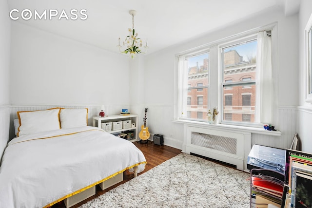 136 E 36th St Unit 9/10C, New York City, NY 10016 - bedroom featuring a wainscoted wall, dark wood finished floors, and a chandelier