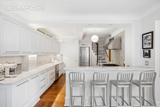 kitchen with ventilation hood, a kitchen breakfast bar, tasteful backsplash, wine cooler, and white cabinetry