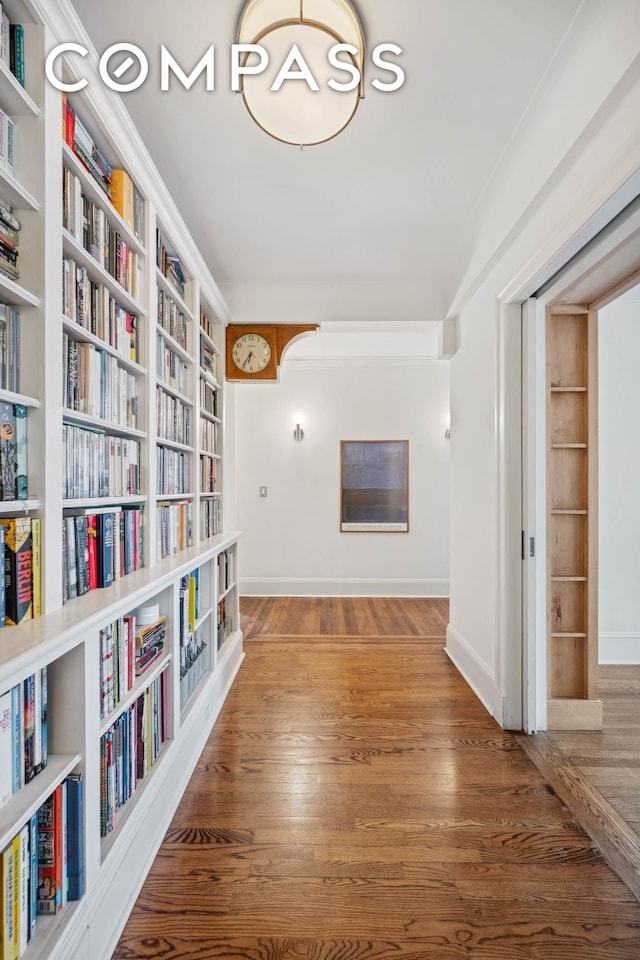 hallway featuring wood finished floors, baseboards, and built in features
